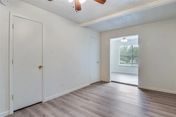 an empty room with wooden floor cabinet and windows