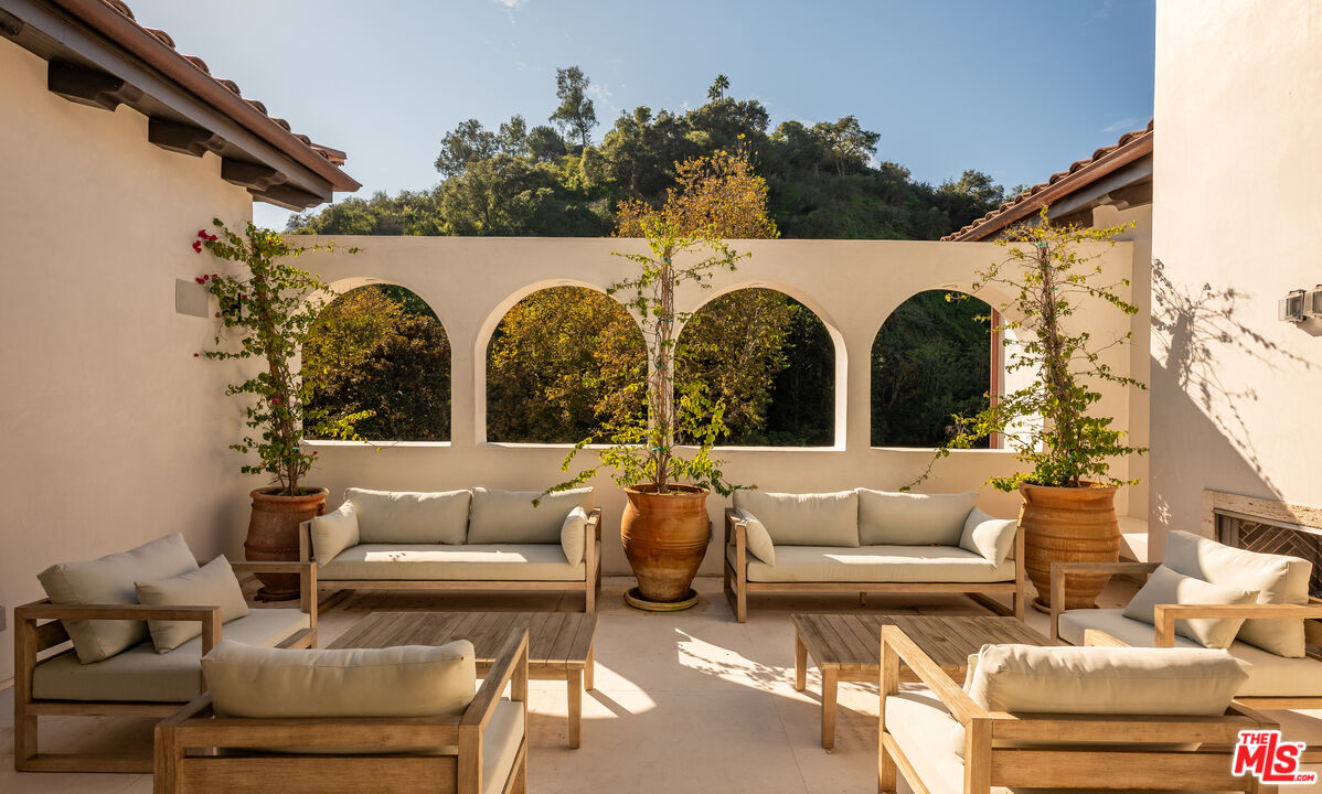 966 Stone Canyon Road Los Angeles, CA 90077 - Photo 18 of 30 a view of a patio with couches chairs and a potted plant