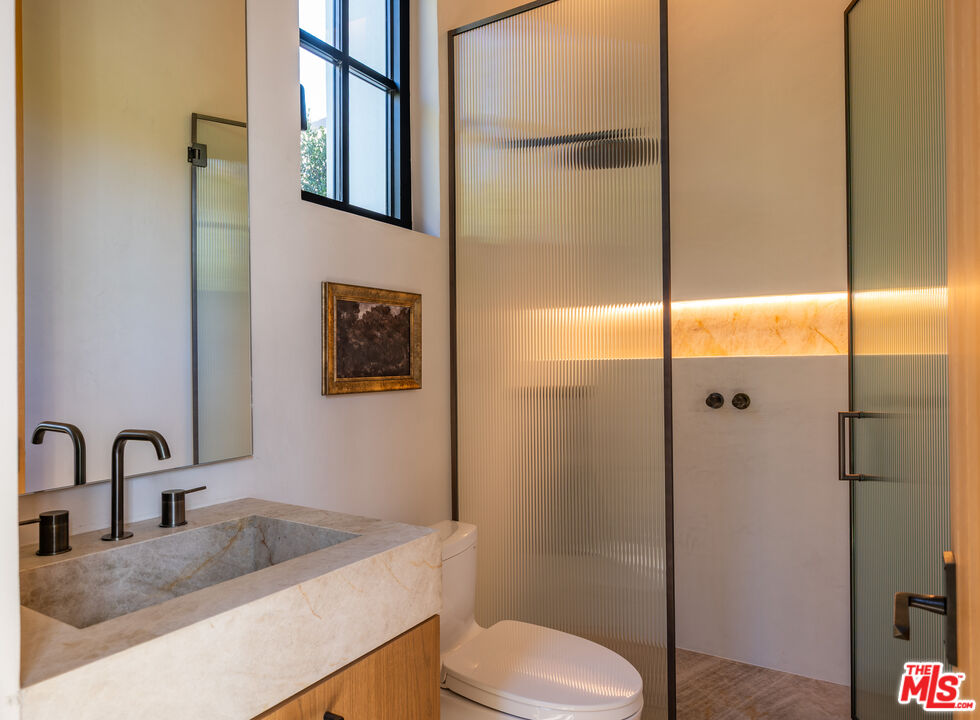 966 Stone Canyon Road Los Angeles, CA 90077 - Photo 19 of 30 a bathroom with a granite countertop sink toilet and shower