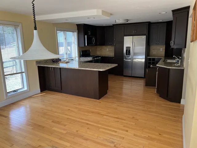 a kitchen with granite countertop a refrigerator and a stove top oven