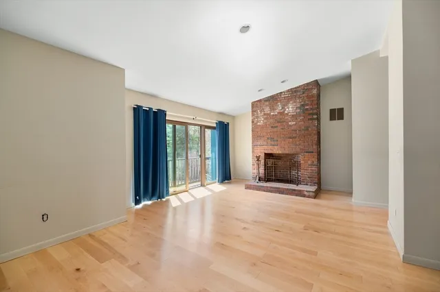 a view of an empty room with a fireplace and a window