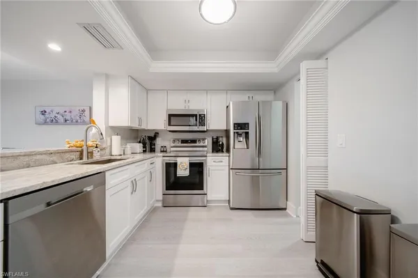 a kitchen with kitchen island granite countertop a sink cabinets stainless steel appliances and a window