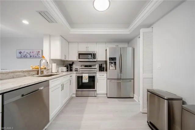 a kitchen with kitchen island granite countertop a sink cabinets stainless steel appliances and a window