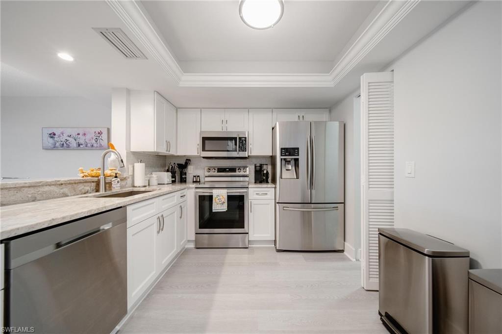 a kitchen with kitchen island granite countertop a sink cabinets stainless steel appliances and a window