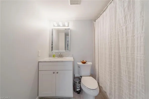 a bathroom with a granite countertop toilet a sink and a mirror