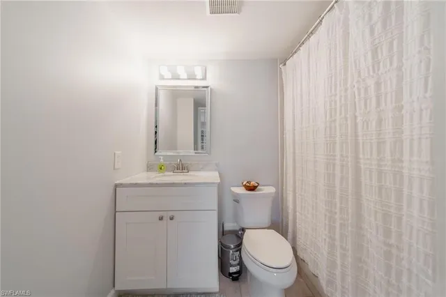 a bathroom with a granite countertop toilet a sink and a mirror