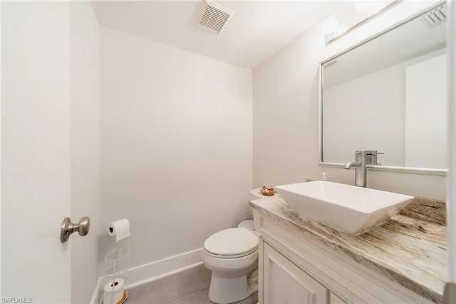 a bathroom with a granite countertop toilet and a sink