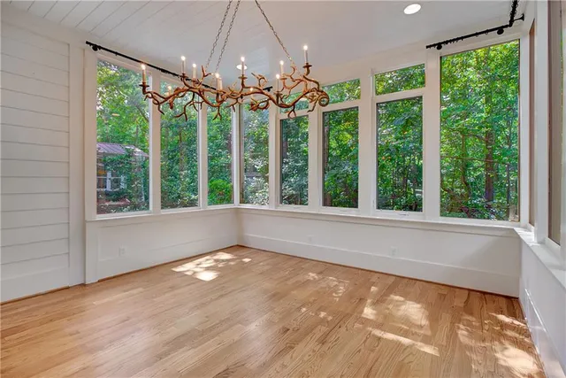 a view of an empty room with wooden floor and a large window