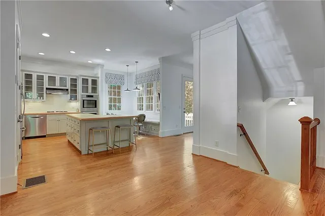 a open kitchen with white cabinets and wooden floor