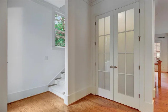 an empty room with wooden floor staircase and windows