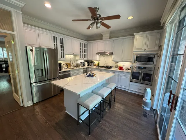 a kitchen with stainless steel appliances a dining table chairs sink refrigerator and cabinets