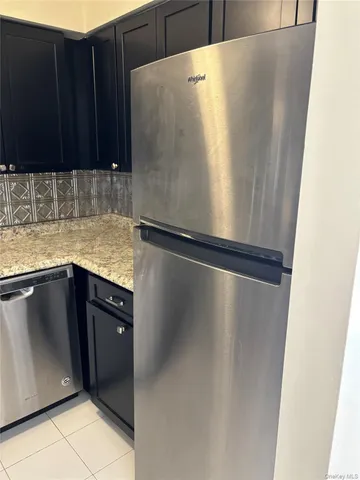 a view of a refrigerator in kitchen with stainless steel appliances wooden cabinet and glass cabinet