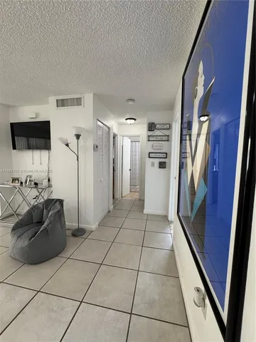 a hallway with a view of kitchen with refrigerator and stove