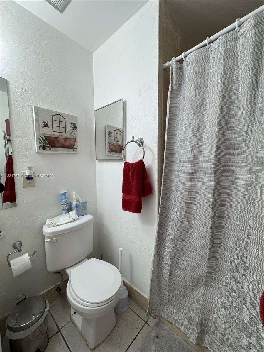 15480 Southwest 82nd Lane, Unit 228 Miami, FL 33193 - Photo 17 of 18 a white toilet sitting next to a shower curtain