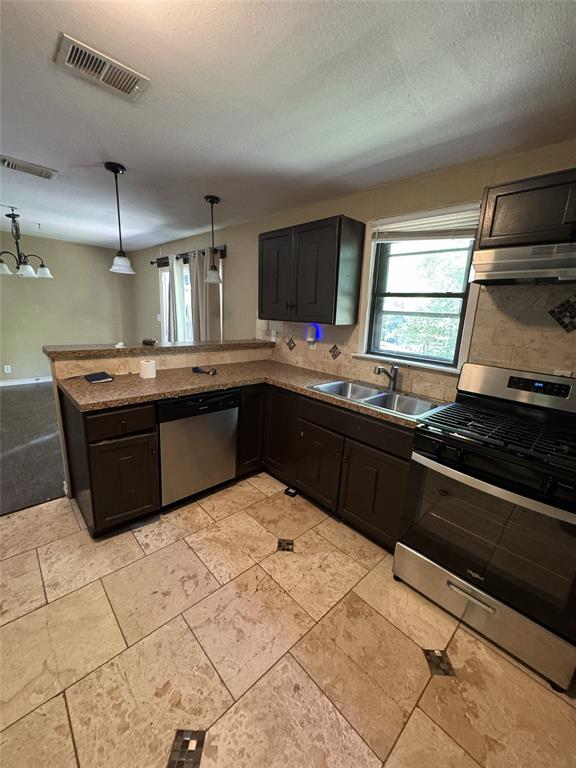 803 Ripley Avenue Ennis, TX 75119 - Photo 13 of 40 Kitchen featuring dark wood cabinetry, stainless steel appliances, a double basin sink, and a tiled backsplash