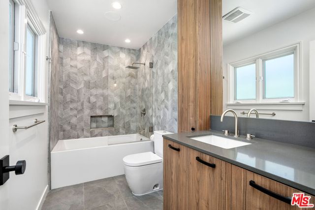 a bathroom with a granite countertop sink a toilet and bathtub