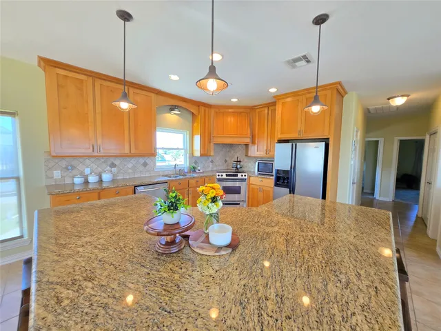 a kitchen with stainless steel appliances granite countertop a sink a stove and a refrigerator