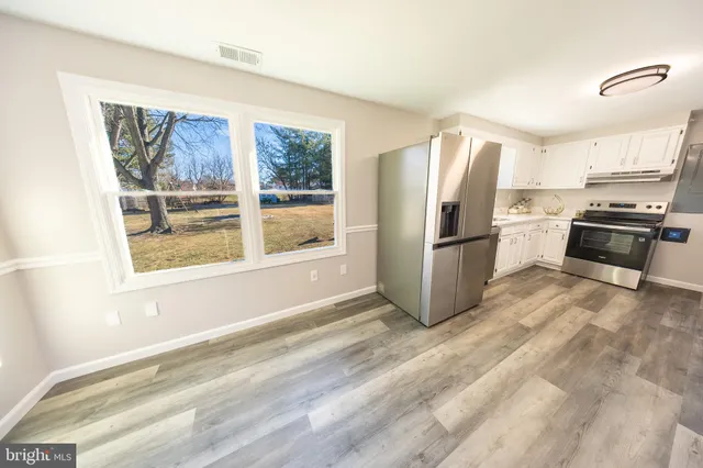 a kitchen with stainless steel appliances granite countertop a refrigerator a stove a sink and a window