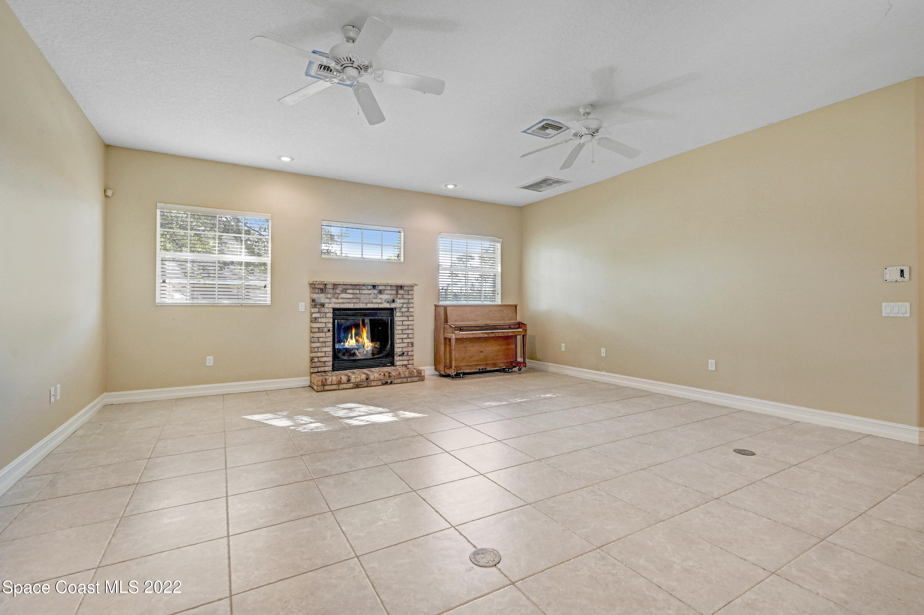 2185 Windbrook Drive Palm Bay, FL 32909 - Photo 43 of 61 a view of an empty room with a fireplace and a chandelier fan