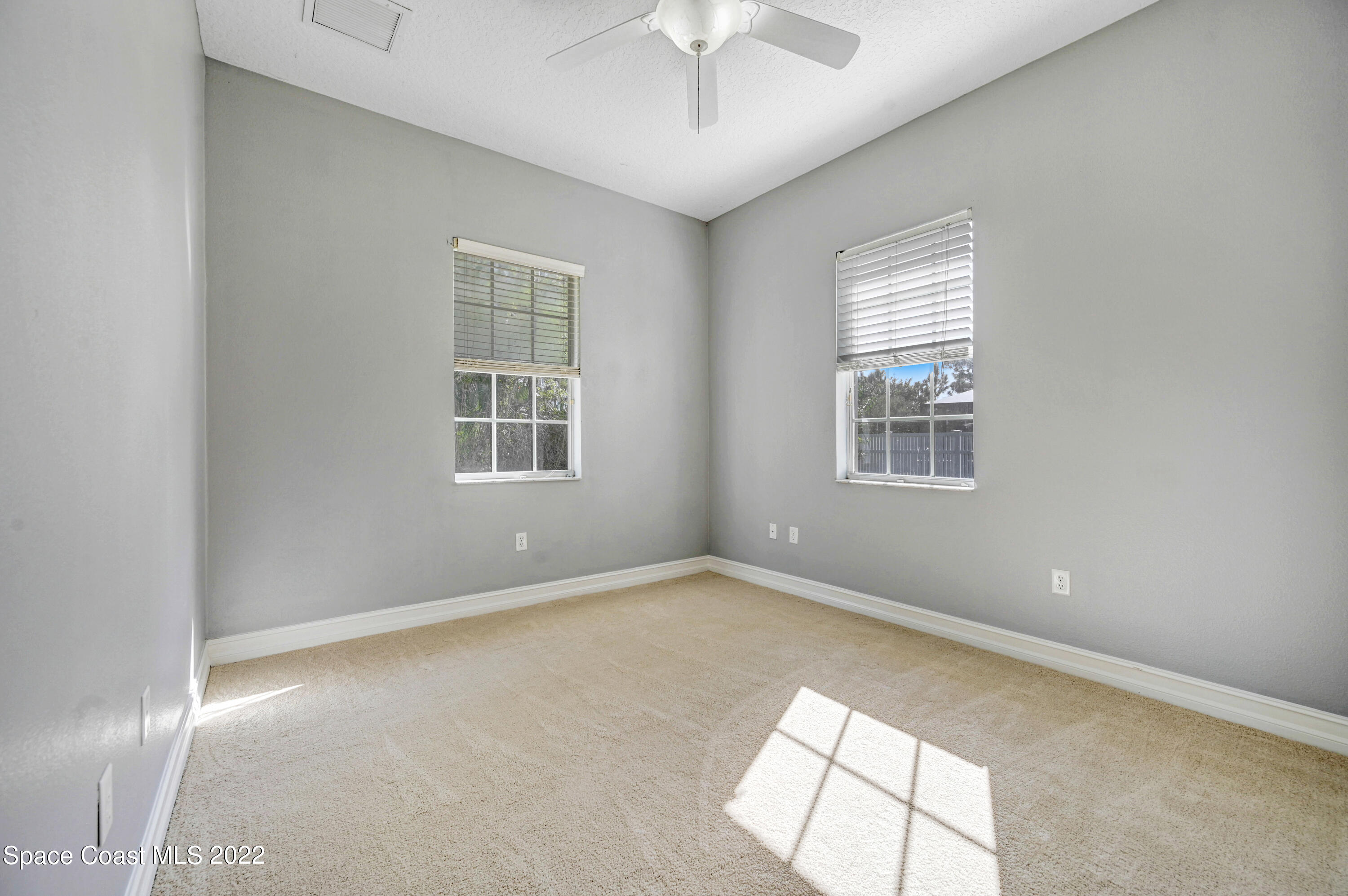 2185 Windbrook Drive Palm Bay, FL 32909 - Photo 58 of 61 an empty room with windows and chandelier fan