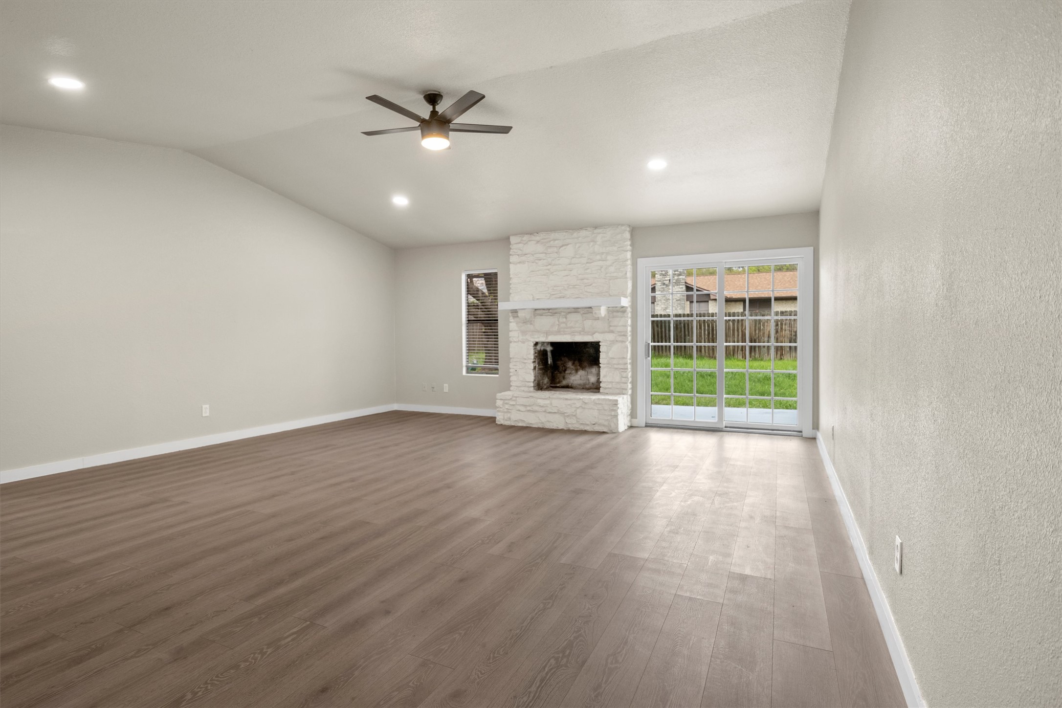502 Pin Tail Lane Taylor, TX 76574 - Photo 14 of 26 Vaulted ceiling living space featuring wood-finish flooring, a white stone-clad fireplace with mantel, and recessed lighting