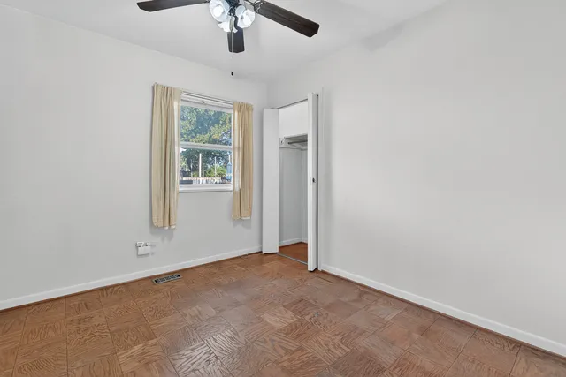 an empty room with windows and fan