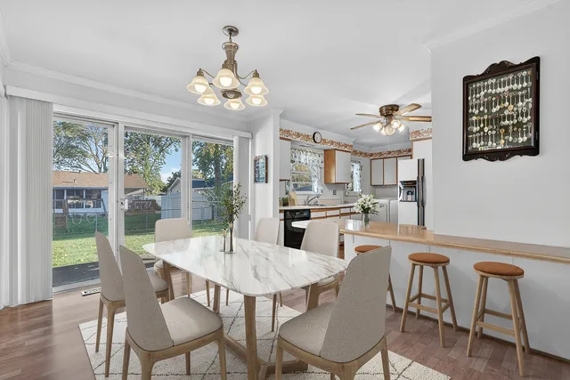a dining room with wooden floor a chandelier a wooden table and chairs