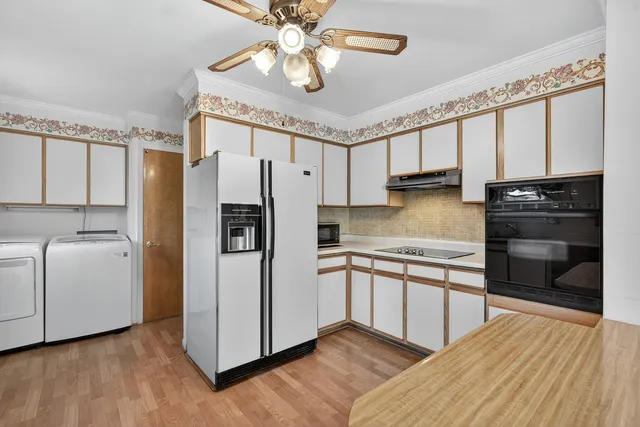 a kitchen with stainless steel appliances a refrigerator a sink and white cabinets