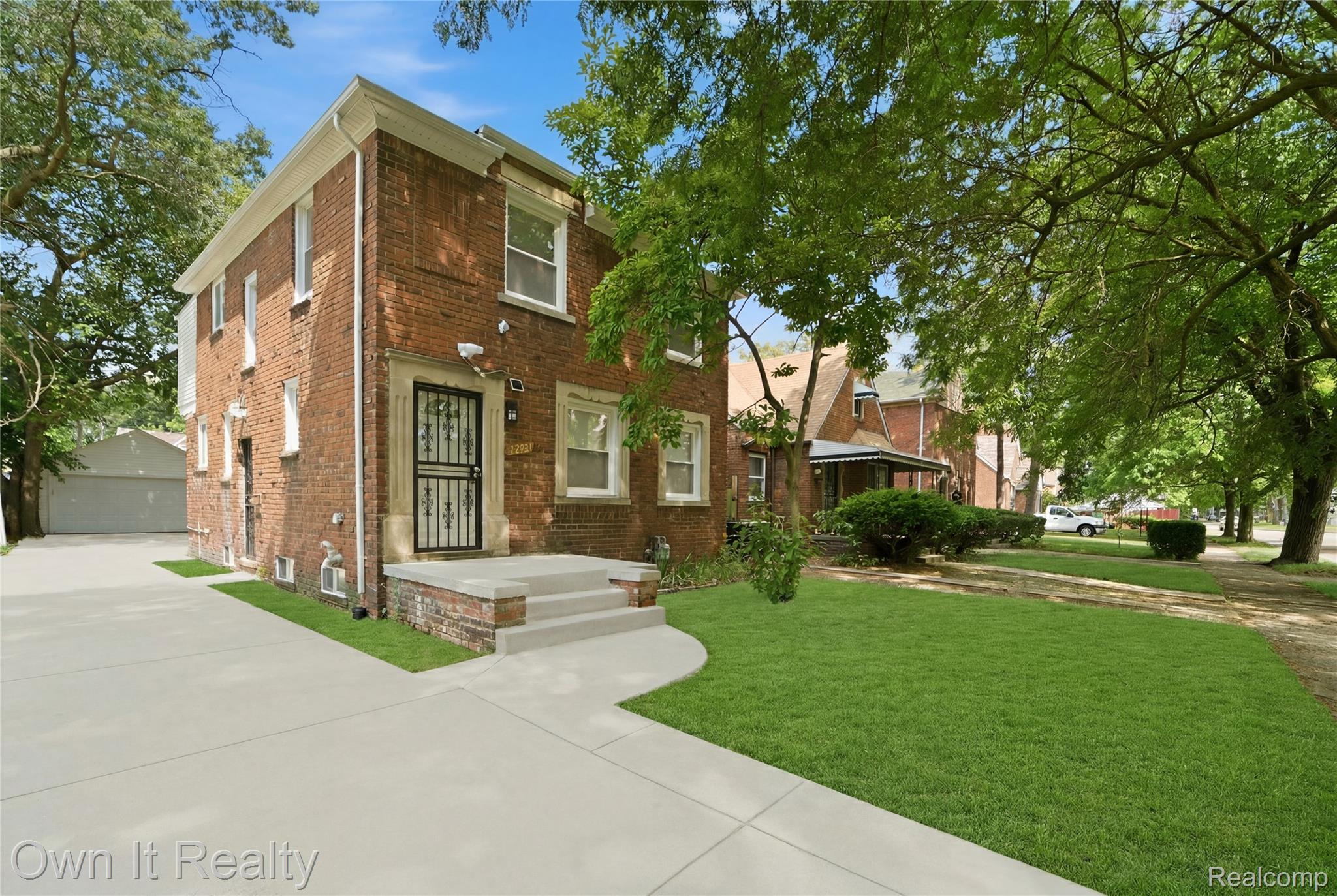 17351 Appoline Street Detroit, MI 48235 - Photo 28 of 34 Brick facade structure featuring a contemporary concrete driveway, a manicured lawn, a detached two-car garage, and a covered entry with security door