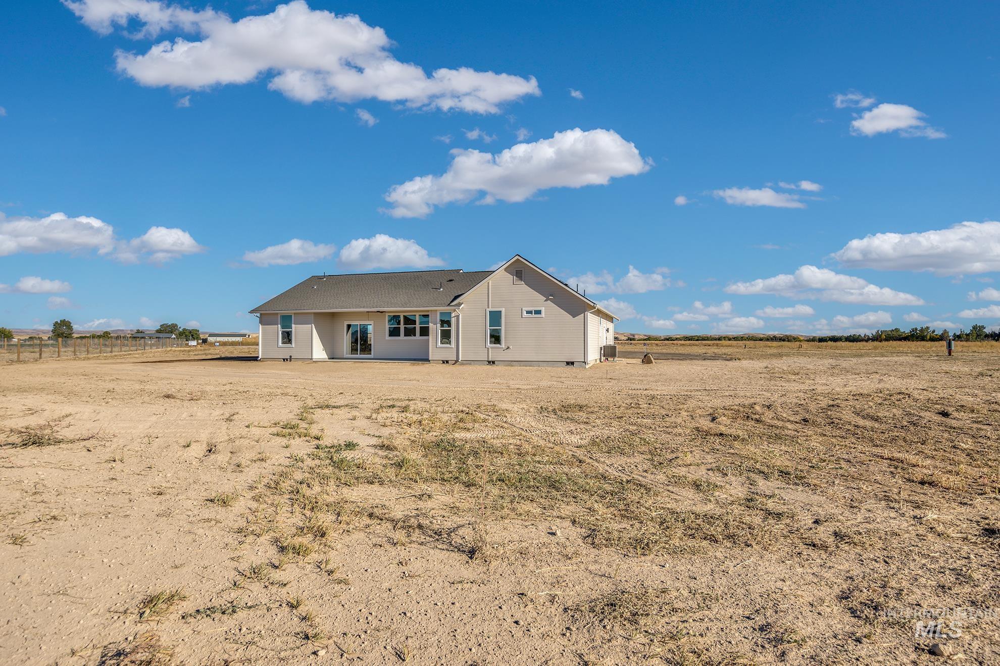 1371 Hansen Road Weiser, ID 83672 - Photo 40 of 44 Single-story residence featuring a neutral-toned exterior, multiple windows, a covered patio, and a shingled roof, all set on an expansive, undeveloped lot