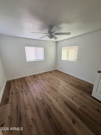 an empty room with wooden floor chandelier and windows