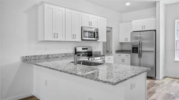 a kitchen with kitchen island granite countertop a sink stove and refrigerator