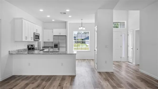 a kitchen with stainless steel appliances granite countertop a refrigerator a sink dishwasher and a stove with wooden floor