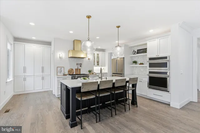 a kitchen with stainless steel appliances kitchen island granite countertop a table chairs stove and white cabinets