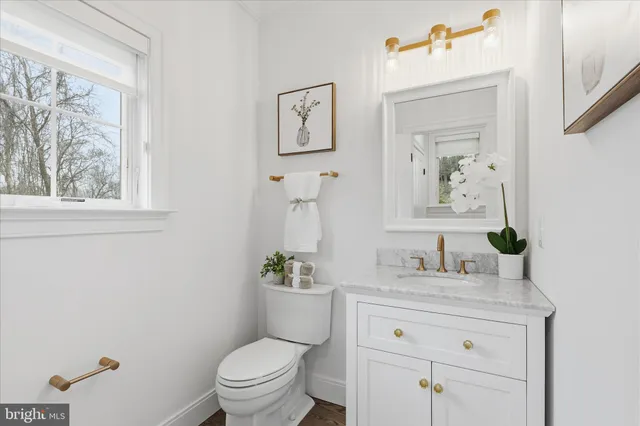 a bathroom with a granite countertop toilet sink and mirror