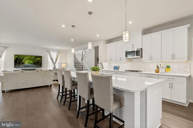 a kitchen with stainless steel appliances kitchen island granite countertop a table chairs sink and cabinets