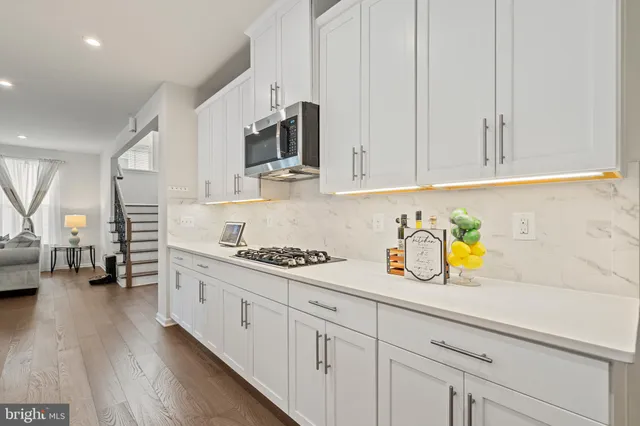 a kitchen with stainless steel appliances kitchen island a white cabinets and chair