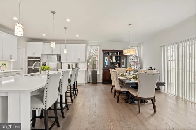 a kitchen with a dining table chairs refrigerator and white cabinets