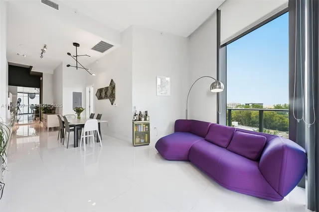 a living room with furniture kitchen view and a large window
