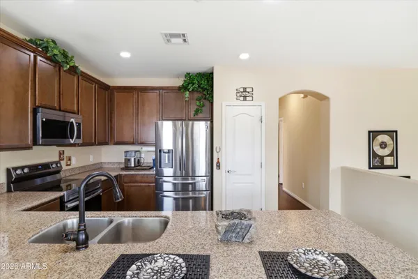 a kitchen with stainless steel appliances granite countertop a refrigerator a stove and a sink with wooden floor