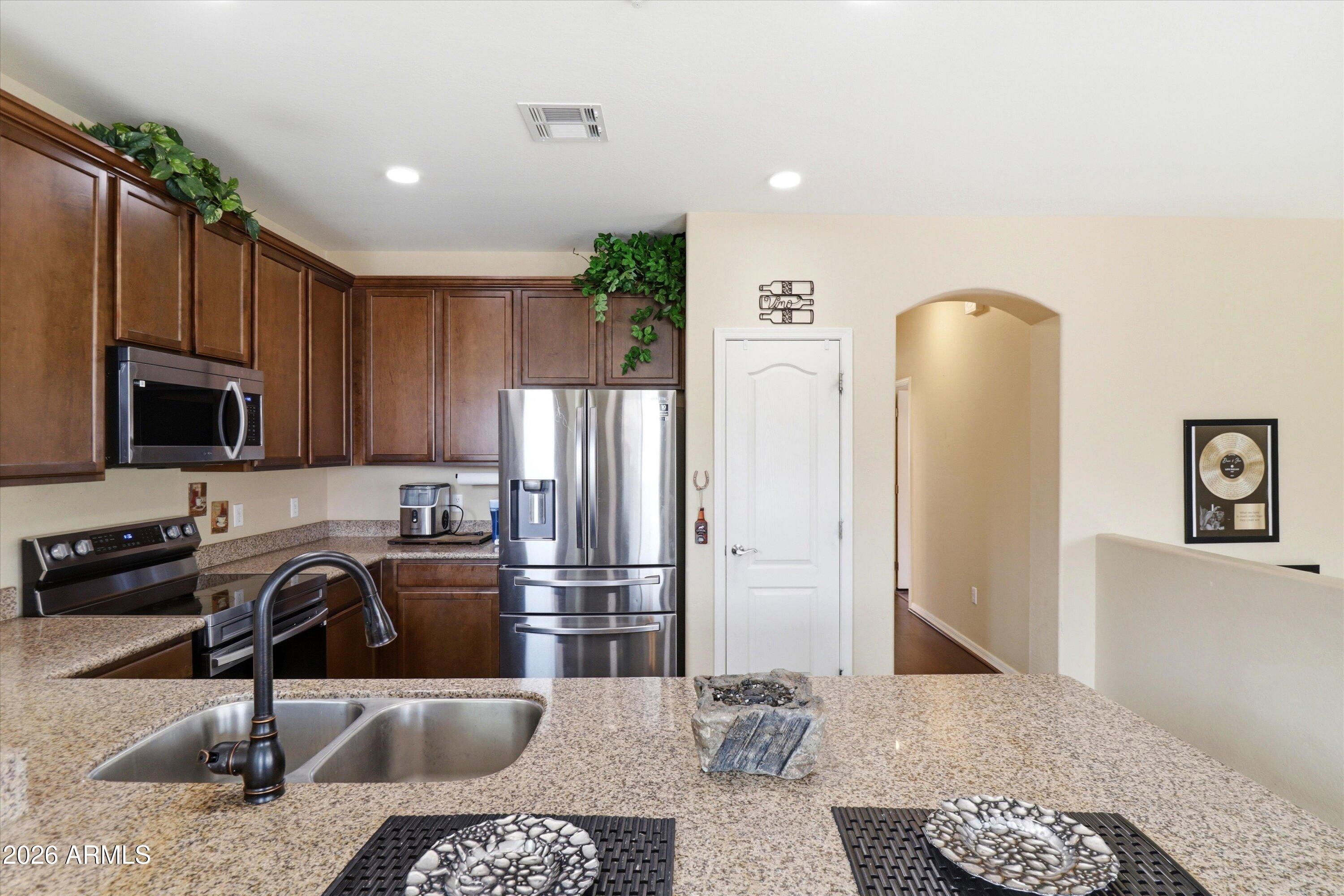 7726 East Baseline Road, Unit 227 Mesa, AZ 85209 - Photo 11 of 22 a kitchen with stainless steel appliances granite countertop a refrigerator a stove and a sink with wooden floor