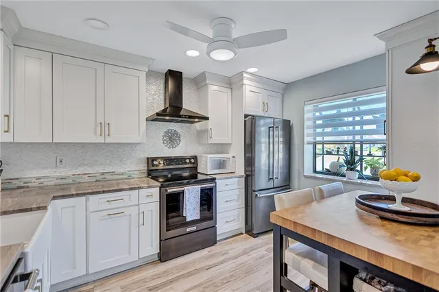 a kitchen with stainless steel appliances a stove a sink dishwasher a refrigerator and white cabinets with wooden floor