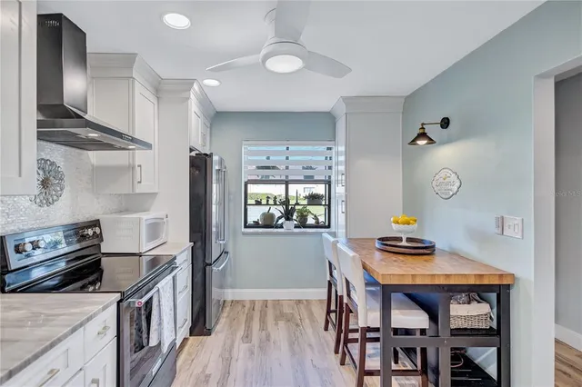 a kitchen with stainless steel appliances granite countertop a stove top oven a dining table and chairs with wooden floor