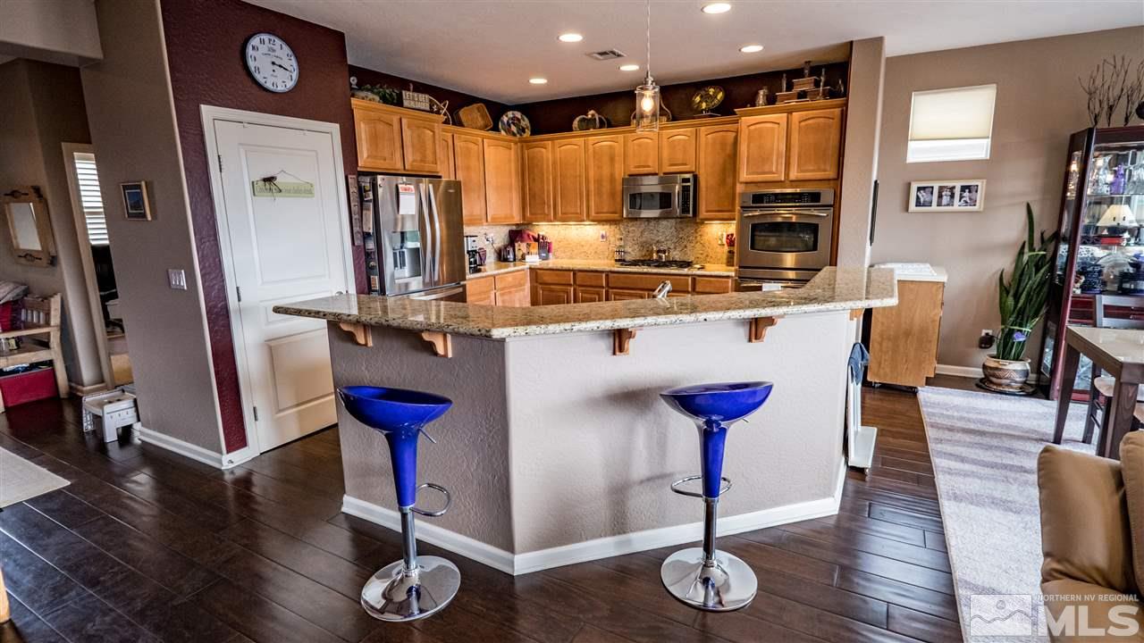1295 Tarleton Way Reno, NV 89523 - Photo 6 of 23 a kitchen with stainless steel appliances granite countertop a refrigerator a stove and white cabinets with wooden floors