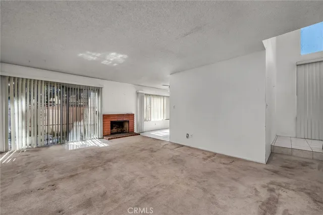 an empty room with windows and fireplace
