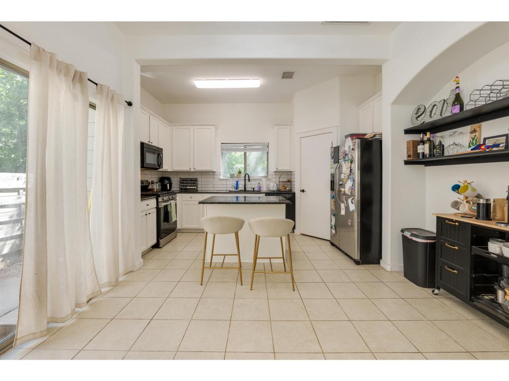 2001 Faro Drive, Unit 53 Austin, TX 78741 - Photo 12 of 34 a kitchen with stainless steel appliances kitchen island granite countertop a refrigerator and a stove top oven