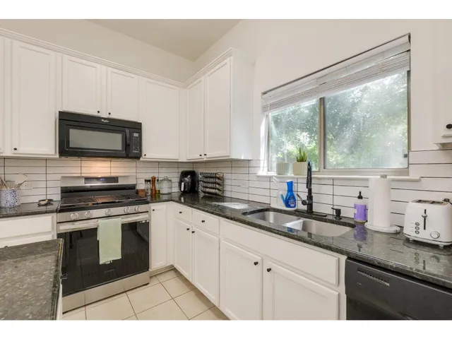 a kitchen with stainless steel appliances granite countertop a stove a sink and a microwave