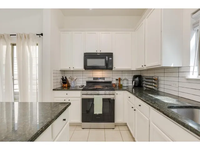 a kitchen with stainless steel appliances granite countertop a sink a stove and refrigerator