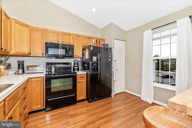 a kitchen with stainless steel appliances granite countertop a stove a sink dishwasher and a refrigerator with wooden floor