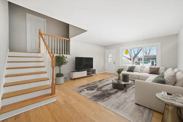 a view of an empty room with wooden floor and stairs